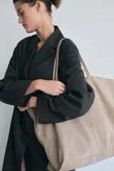 Bolso tipo maxi shopper color beige de ante, con doble asa de hombro y bolsillo interior con cremallera.