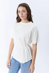 Remera blanca de manga corta con cuello redondo y pinzas laterales que crean un drapeado en la parte delantera.