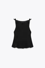Top negro con cuello barco, sin mangas y detalle de lazos en los hombros. Corte peplum en la parte inferior.