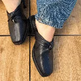 Zuecos negros de cuero con punta cuadrada y detalle de nudo en el empeine.