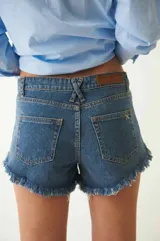 Short de jean azul con tiro bajo, efecto desgastado y flecos en el ruedo.