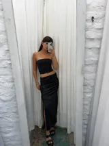 Pollera midi negra de satén con frunces laterales y abertura en la pierna.