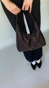 Cartera tipo baguette negra de lona semi impermeable con cierre metálico y forrería de gross con bolsillo interno.