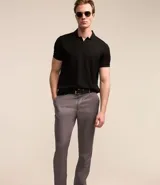 Pantalón de vestir gris, de corte slim fit, con bolsillos laterales y traseros. Se ajusta a la cintura con cinturón de cuero negro.