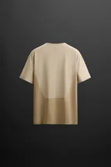 Remera deportiva marrón de tejido técnico, ligero y elástico con estructura perforada. Cuello redondo, manga corta, bajo asimétrico con aberturas laterales, costuras termofijadas y logo estampado.