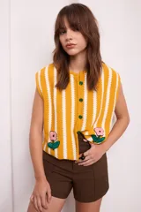 Chaleco tejido a crochet con rayas verticales amarillas y blancas, con botones verdes y apliques florales bordados.