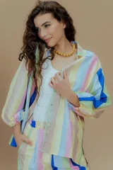 Camisa de mangas largas con puños elásticos y cuello clásico. Presenta un estampado a rayas verticales de colores pastel y cierre frontal con botones.