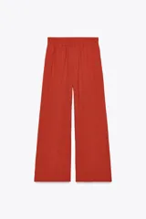 Pantalón color ladrillo de tiro alto con cintura elástica, bolsillos delanteros y pernera ancha.