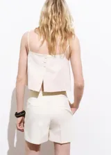 Short color crema de tiro medio y diseño recto, con cierre oculto de botón, gancho y cremallera, y forro interior.