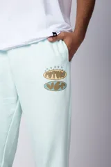 Pantalón de jogging negro de corte oversize, con puños elásticos y estampado con la palabra 'FUTURO' en verde y amarillo.