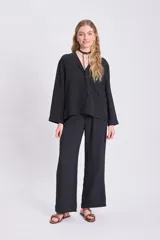 Blusa negra de manga larga con cuello en V y cierre con botones.