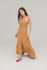 Vestido largo color ocre con estampado de hojas, escote halter cruzado y falda acampanada con volantes.