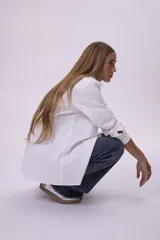 Camisa blanca de corte clásico, con cuello camisero y mangas largas.