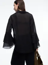 Camisa negra de lyocell y poliamida, con cuello clásico, mangas largas acampanadas con volados y cierre frontal con botones.