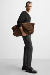 Pantalón negro de corte slim fit, confeccionado en tejido elástico. Cuenta con cintura elástica, bolsillos frontales y traseros de vivo. Cierre frontal con cremallera y botón.