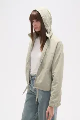 Campera de corte holgado en color tostado, confeccionada en poliamida. Presenta cuello alto, cierre frontal con cremallera, bolsillos laterales con cierre y cordón ajustable en el ruedo.