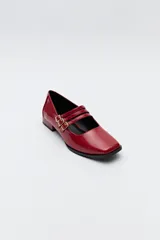 Zapato tipo Mary Jane color negro con textura de reptil, de charol sintético con punta cuadrada y triple tira con hebillas.
