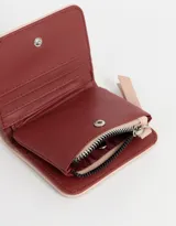 Billetera pequeña color rosa con textura símil cuero, cierre superior con cremallera y tiras de cuero sintético.