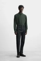 Camisa de vestir verde oscuro, corte slim fit, con cuello italiano, mangas largas con puños abotonados y cierre frontal con botones.
