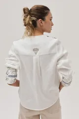 Camisa blanca de lino con bordados florales en tonos beige y azul.