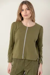 Remera verde militar de algodón con cuello redondo y mangas largas abullonadas. Presenta un detalle de cinta plateada en el frente, puños y tajos laterales.