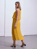 Vestido largo color mostaza, sin mangas, con escote redondo y detalle de crochet en los hombros.