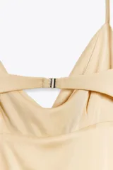 Vestido largo color beige de tejido de punto, con escote drapeado y tirantes finos ajustables. Espalda descubierta con escote drapeado y tira con gancho metálico.
