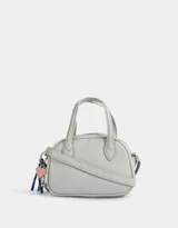 Cartera bowling gris claro de cuerina con doble asa corta de mano, correa regulable y cierre superior. Incluye charm lateral.