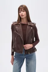 Chaleco estilo biker de eco-cuero color marrón oscuro, con solapas anchas, cierre frontal asimétrico y detalles de tachas plateadas. Presenta cinturón ajustable con hebilla en el ruedo.