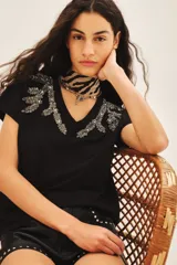 Remera negra de algodón modal con calce holgado y cuello en V. Presenta bordados de inspiración botánica con piedras, lentejuelas y mostacillas en el escote.