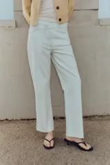 Jeans tobilleros de tiro alto color blanco, corte recto y bajo sin costura. Cierre frontal cruzado con cremallera y botones.