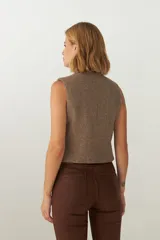 Chaleco marrón de lana con escote en V y cierre con botones.