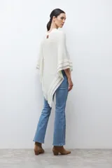 Capa tejida color negro, con cuello redondo, diseño de punto y detalles de lentejuelas. Presenta flecos en el dobladillo.