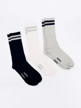 Pack de tres pares de medias de caña corta, estilo deportivo, con franjas en el borde superior. Incluye un par azul marino, un par blanco hueso y un par gris claro.