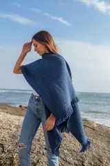 Ruana azul marino de tejido grueso con flecos en el borde.