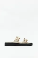 Sandalias marrones con plataforma baja y tiras anchas con hebillas metálicas.