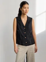 Camisa negra sin mangas con cuello camisero, cierre frontal con botones y pespuntes en color crudo.