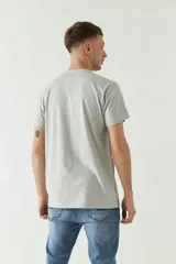 Remera gris de manga corta con estampa fotográfica de un edificio enmarcada en un cuadrado negro.