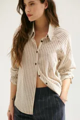 Camisa a rayas verticales color beige y blanco, con cuello clásico, botones marrones y mangas largas.