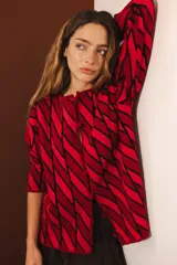 Cárdigan tejido con diseño de rombos rojos y negros, con mangas largas y cierre frontal con botones.