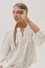 Blusa blanca de algodón con hilos metalizados, cuello mao y escote en V.