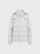 Campera puffer Moncler Maya color gris claro, rellena de plumas, con capucha desmontable, cierre frontal con botones a presión y bolsillos laterales con cierre.