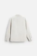 Camisa color crema de corte relaxed fit, confeccionada en tejido de mezcla de algodón suave al tacto. Tiene cuello solapa, manga larga con puños abotonados, un bolsillo de parche en el pecho y cierre frontal con botones.