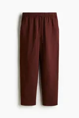 Pantalón tobillero marrón de corte holgado en tejido liviano de mezcla de lino. Modelo de tiro alto con elástico revestido y cordón para ajustar fino en la cintura, bolsillos al bies y piernas ajustadas.