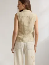 Camisa color beige claro sin mangas, con cuello camisero y cierre frontal con botones.