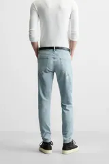 Pantalón de jean negro con corte skinny fit, cinco bolsillos, lavado con efecto roto y cierre frontal con cremallera y botón.