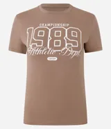 Remera marrón de algodón con cuello redondo, mangas cortas y estampado frontal con el número 1989 y texto en color blanco.