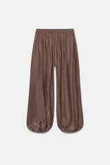 Pantalón bombacho marrón de tejido fluido, tiro medio con cintura elástica ajustable con cordones, bolsillos laterales ocultos y bajo abullonado con elástico interior.