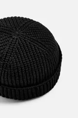 Gorro negro corto de punto con ajuste con trabilla y acabado con vuelta.