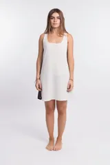 Vestido corto de punto waffle color crudo, con cuello redondo y sisas con ribete marrón. Presenta un logo bordado en el pecho y una banda lateral marrón.